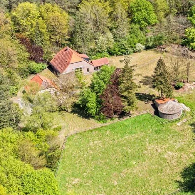 Luchtfoto van het oorspronkelijke huisje van het Windmolenveld, klein en bescheiden te midden van het groen